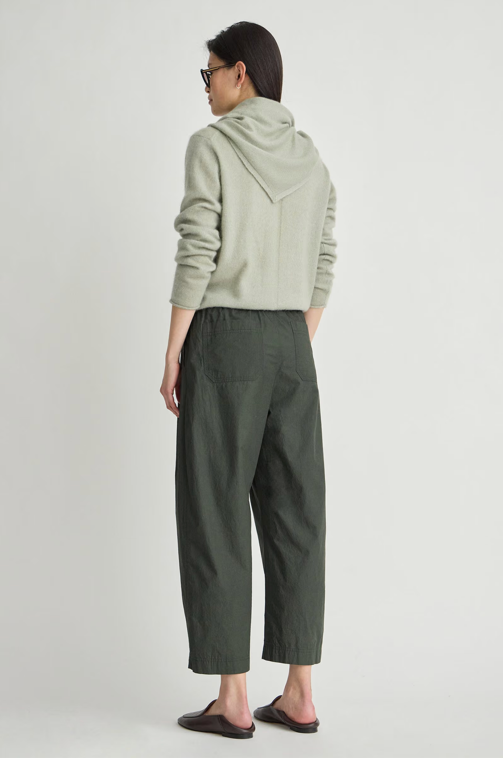 Apiece Apart Spa Pleat Pant styled with a light hoodie, shown from the back against a simple backdrop.