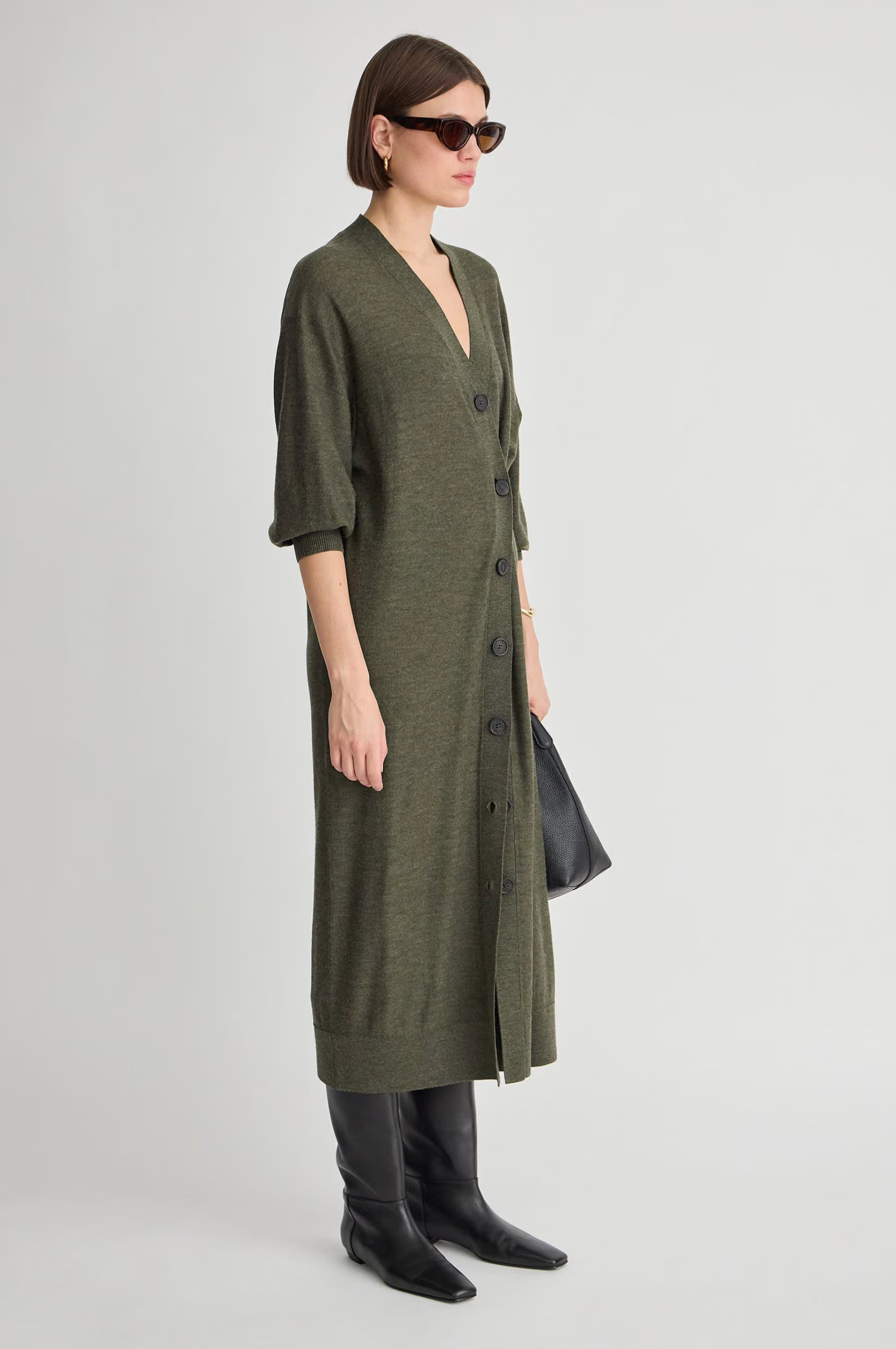 Apiece Apart Drippy Cardi Dress in cream, styled with black boots and bag, modeled in a modern lifestyle setting.