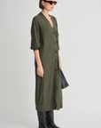 Apiece Apart Drippy Cardi Dress in cream, styled with black boots and bag, modeled in a modern lifestyle setting.