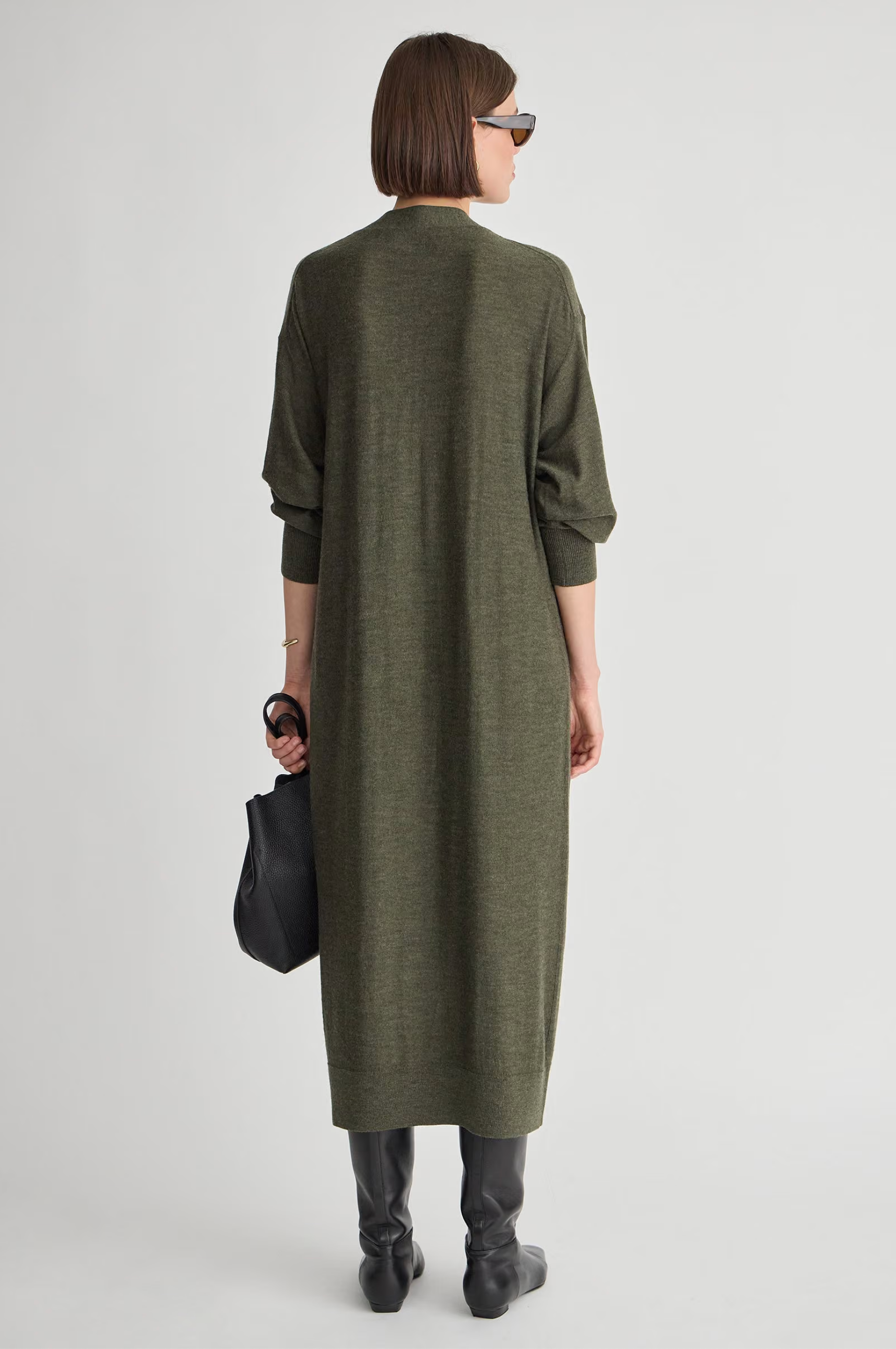 Apiece Apart Drippy Cardi Dress in a relaxed fit, paired with black boots and bag, model facing away.