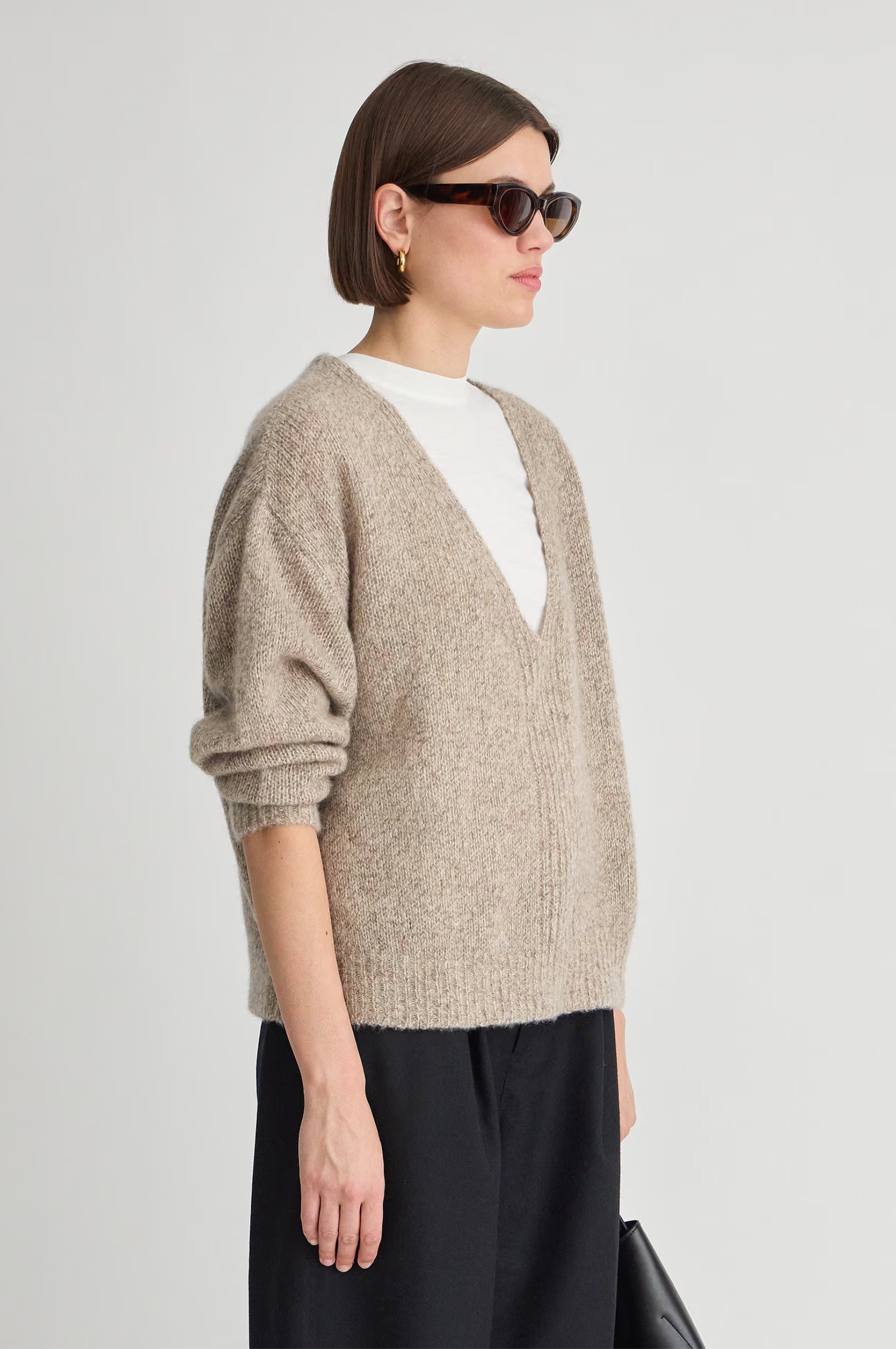 Apiece Apart silk cashmere V-neck marl sweater in soft hue, styled with white top and black pants.