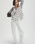 The Everything Shirt by Sold Out NYC in white, styled with sandals and a black bag against a plain backdrop.