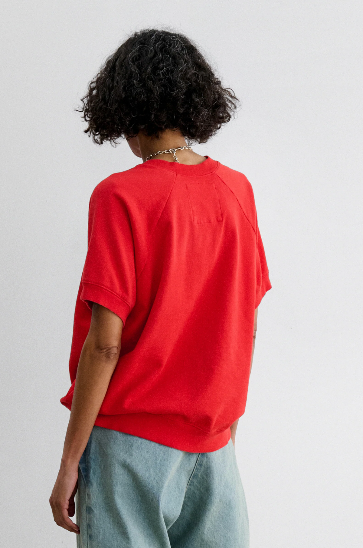 Red Rachel Comey Billi Sweatshirt styled with light blue jeans, model shown from behind, casual look.