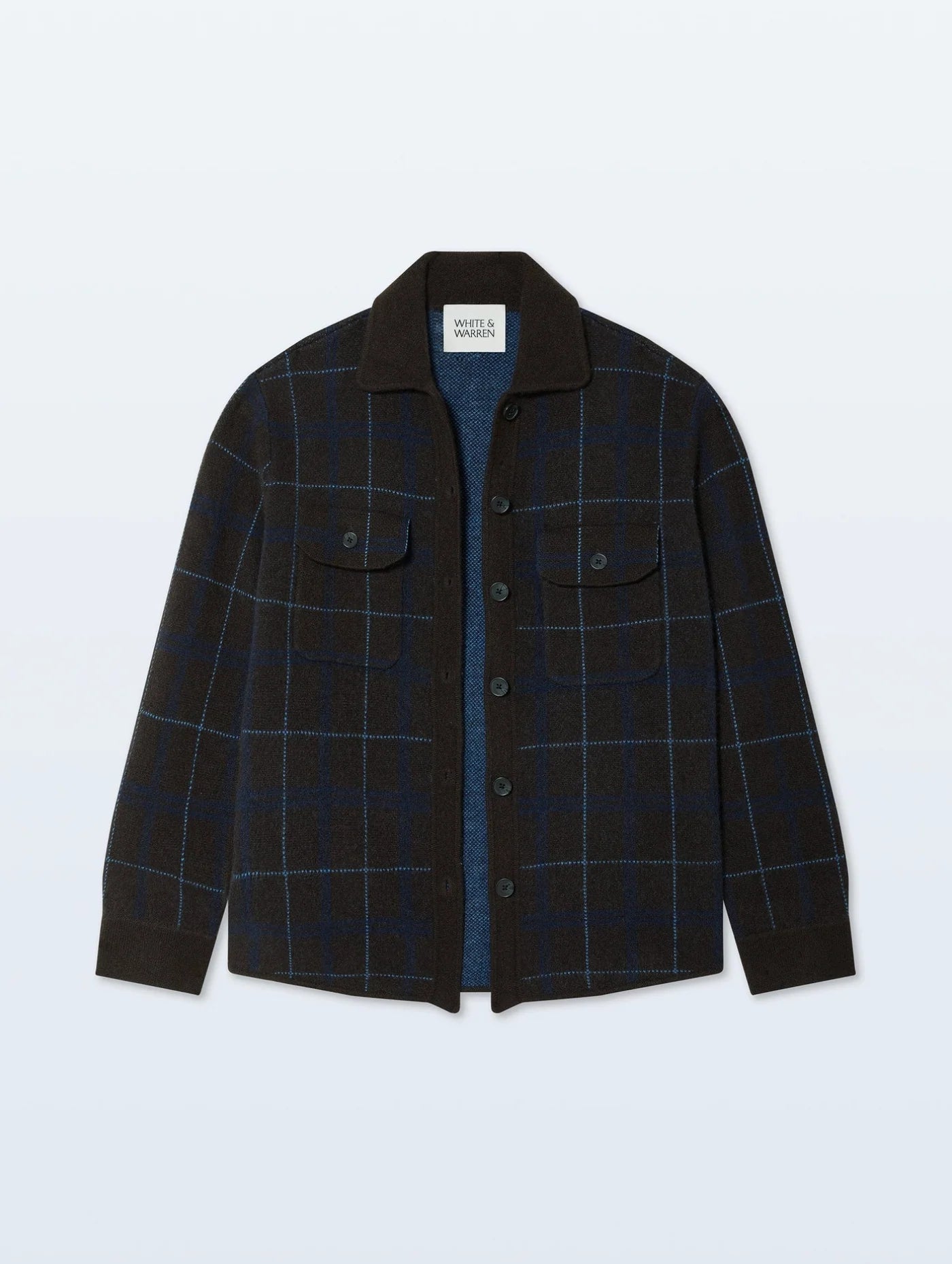 The White + Warren Cashmere Plaid Shacket is a women's long-sleeve, button-up layer featuring a black and blue plaid pattern, two flap chest pockets, and a black collar—shown on a simple light background.