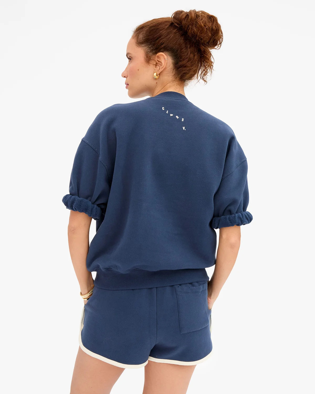 Blue Clare Vivier oversized short sleeve sweatshirt shown from the back, modeled by woman with curly hair in a bun.