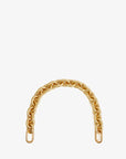 The Shortie Strap by Clare Vivier, featuring large brass spring links in a gold finish, forms an elegant arch on a plain white background, bringing sophistication to any bag accessory collection.