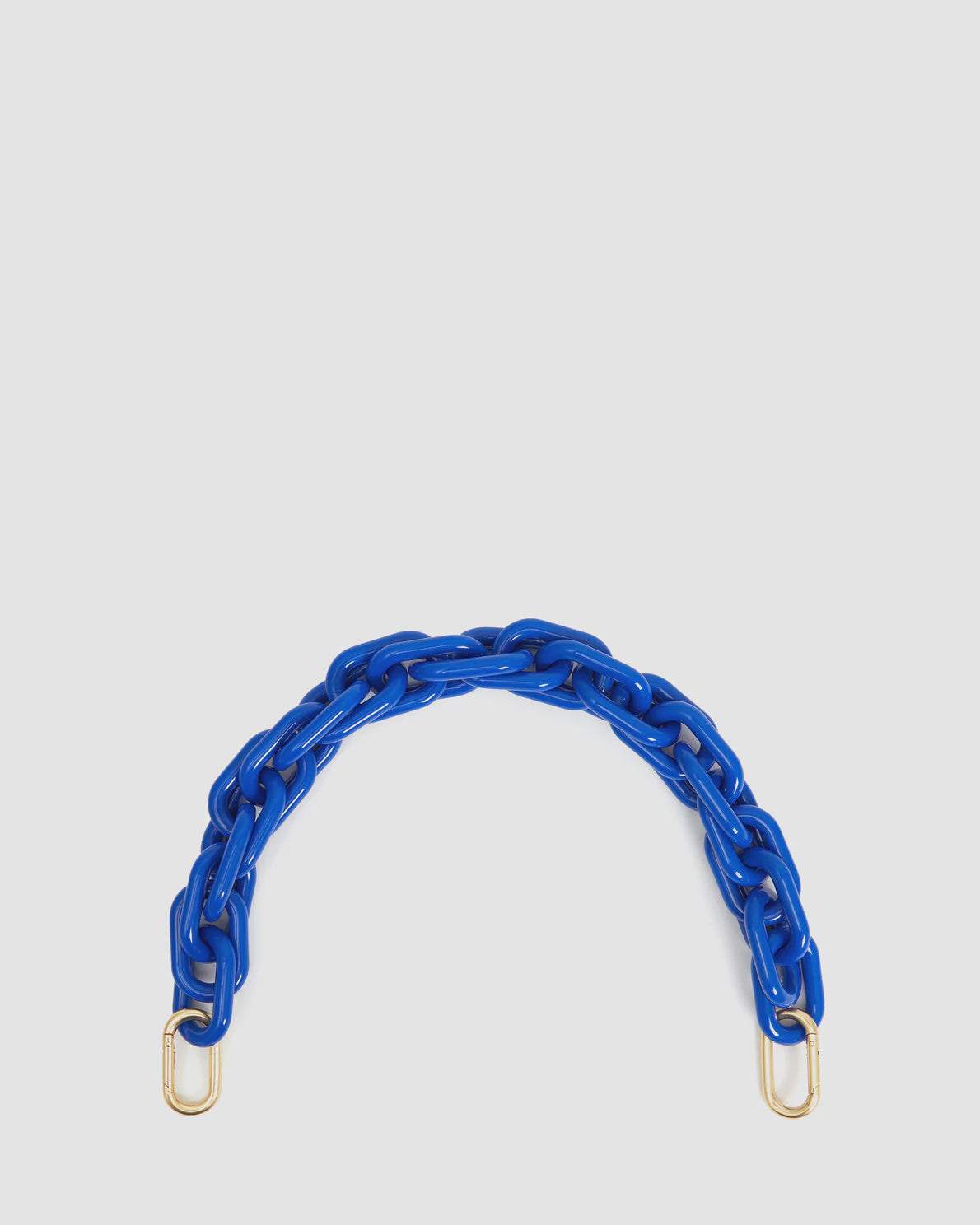 A blue, chunky resin chain strap measuring 17" long features brass spring links and gold-colored clasps at both ends, laid out in a curved shape against a plain white background. This is the Shortie Strap by Clare Vivier.