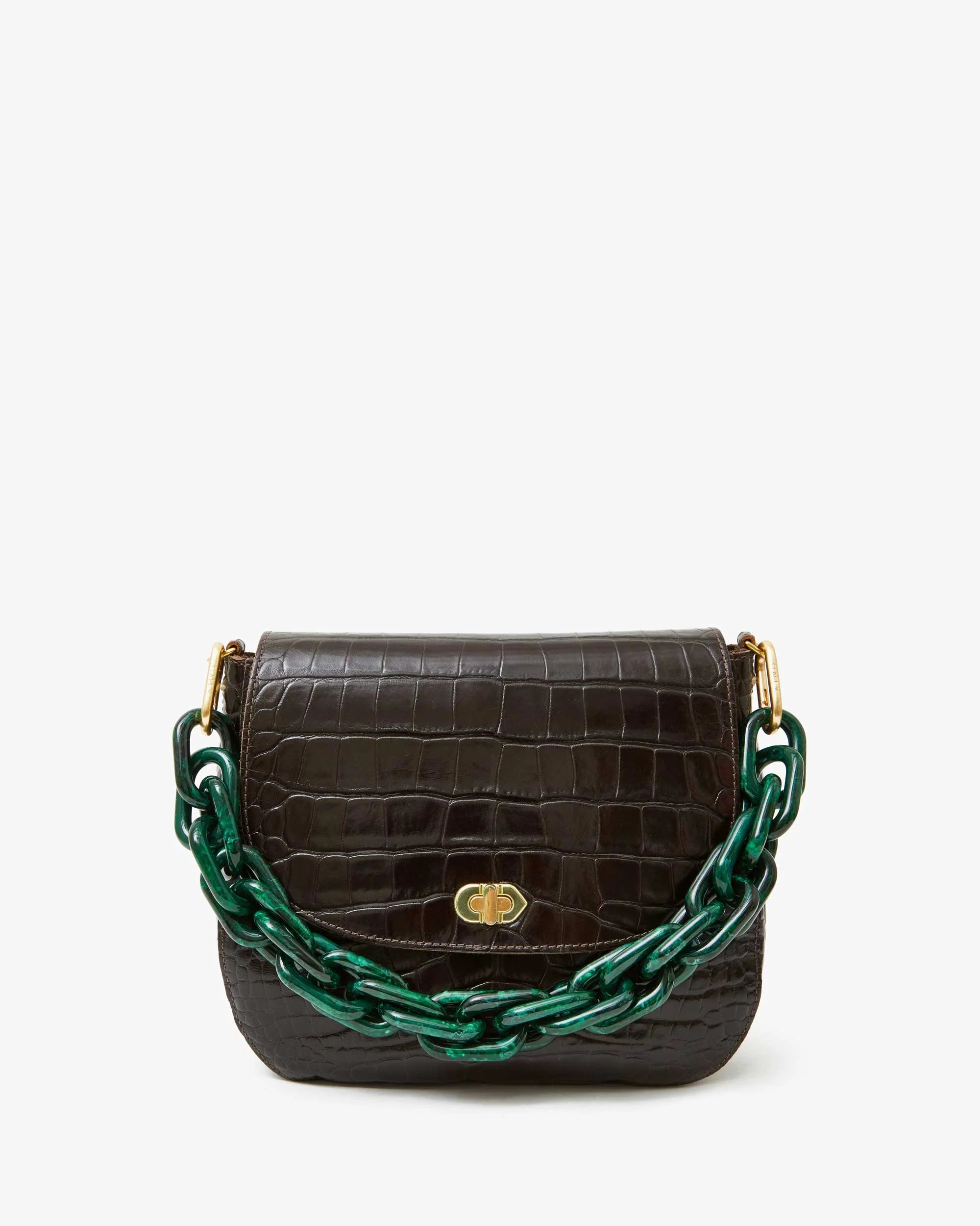 The Shortie Strap by Clare Vivier is a small dark brown leather handbag with crocodile texture and a gold clasp. It has a thick, dark green resin chain strap attached to brass spring links, showcased against a plain white background.