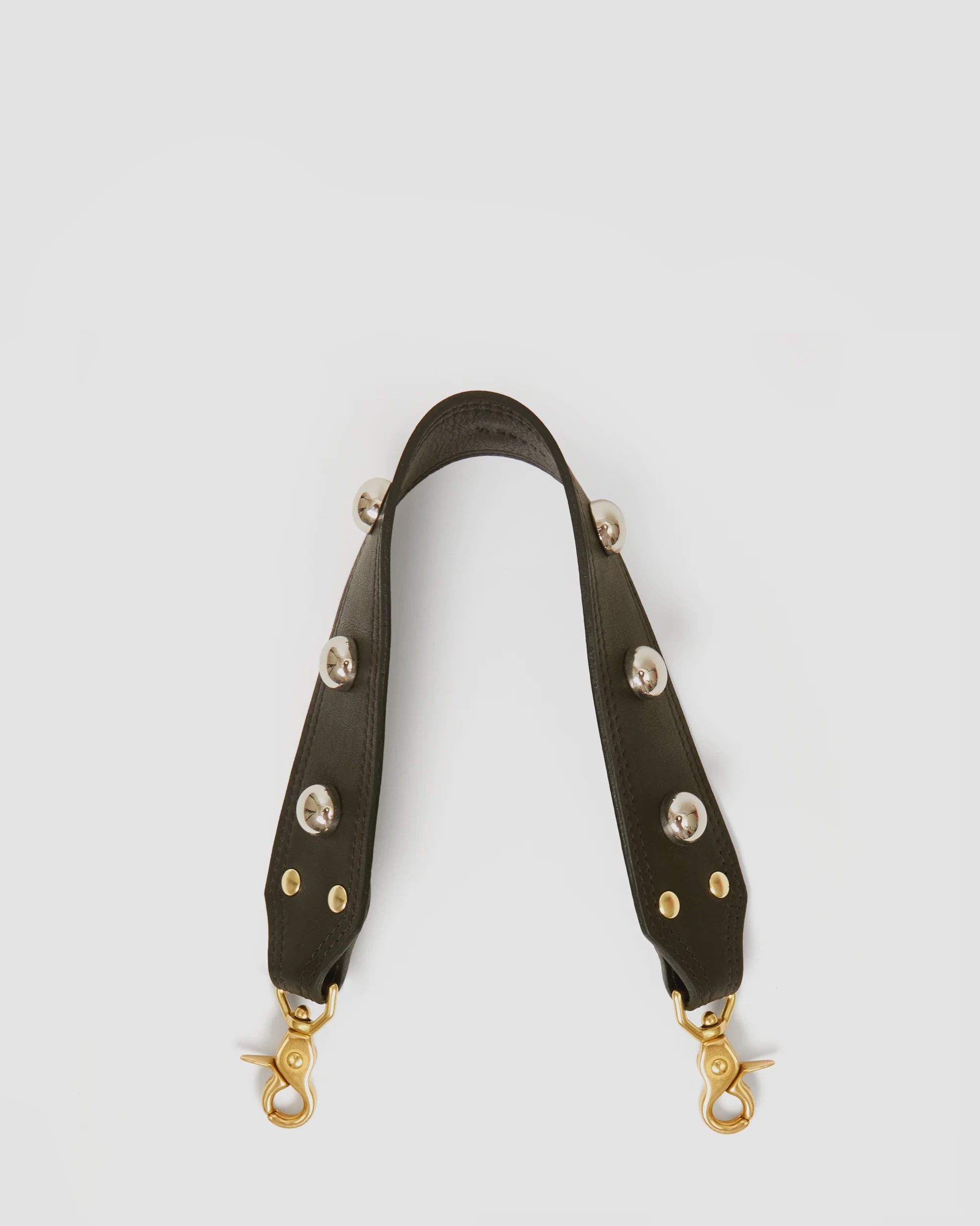 The Clare Vivier Shoulder Strap Naturelle W/ Studs is a detachable dark leather strap for a shoulder bag, featuring brass studs and gold-tone lobster clasps, shown against a plain white background.