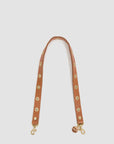 The Clare Vivier Shoulder Strap w/Grommets is a tan Italian leather bag strap with large brass grommets, gold clasps at each end, and a small round Clare Vivier tag near one clasp.