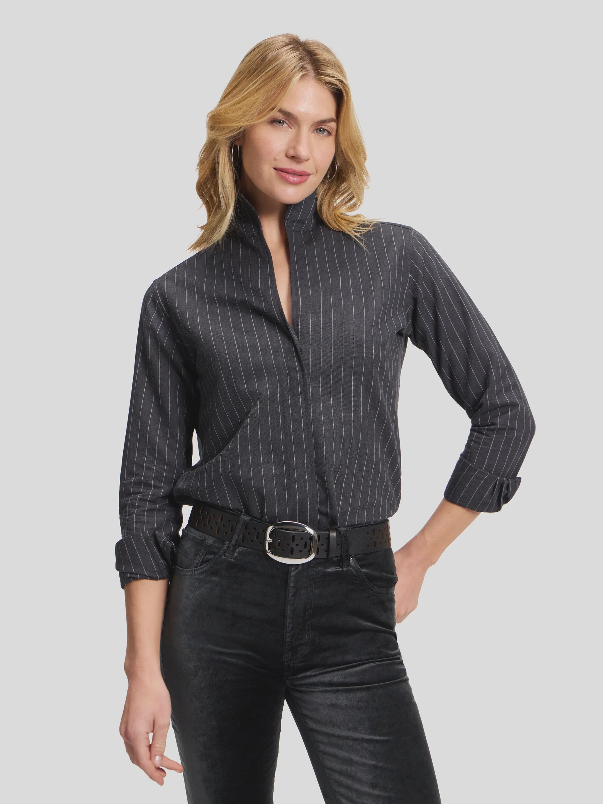 Charcoal pinstripe shirt by Sarah Alexandra, sleeves rolled; worn with a confident smile in a modern setting.