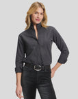Charcoal pinstripe shirt by Sarah Alexandra, sleeves rolled; worn with a confident smile in a modern setting.