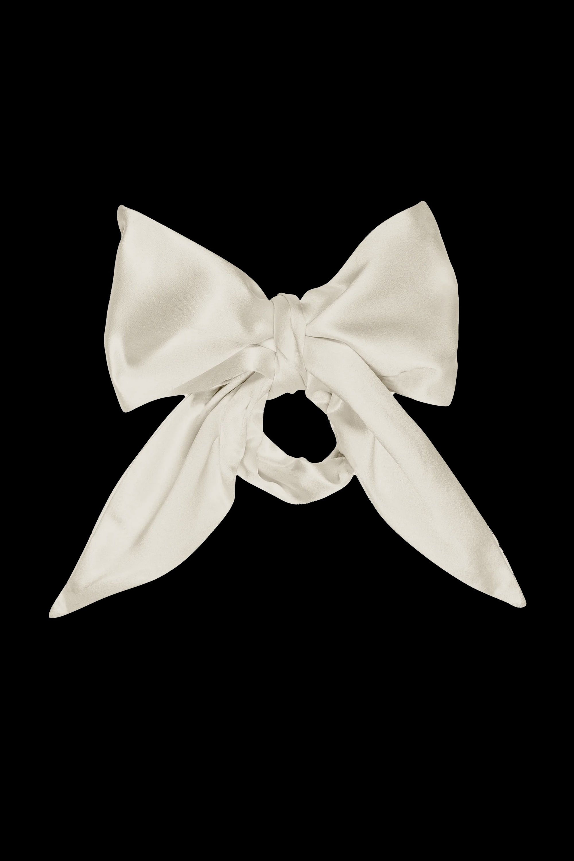 The Silk Bow by Donni is a luxurious accessory crafted from 100% silk fabric, elegantly showcased against a solid black background. It features long, flowing tails and smooth, shiny material for an opulent appearance.