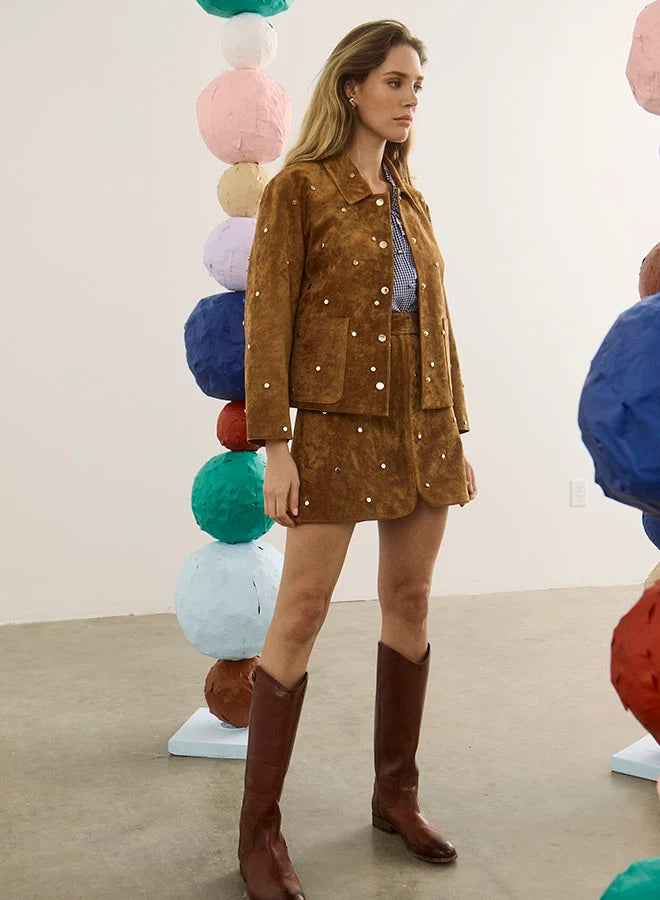 Hunter Bell NYC Hanlin Jacket and skirt styled with tall boots in a modern gallery featuring colorful sculptures.