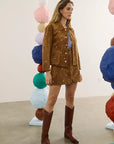 Hunter Bell NYC Hanlin Jacket and skirt styled with tall boots in a modern gallery featuring colorful sculptures.