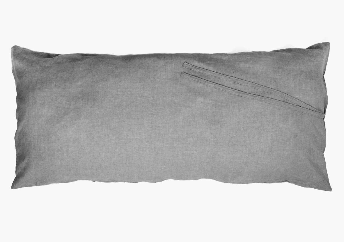 The Hedgehouse Throwbed is a rectangular gray pillow with a subtle seam and two thin fabric ties on the top right corner. It features a removable, machine-washable cotton cover and is pictured against a plain white background.
