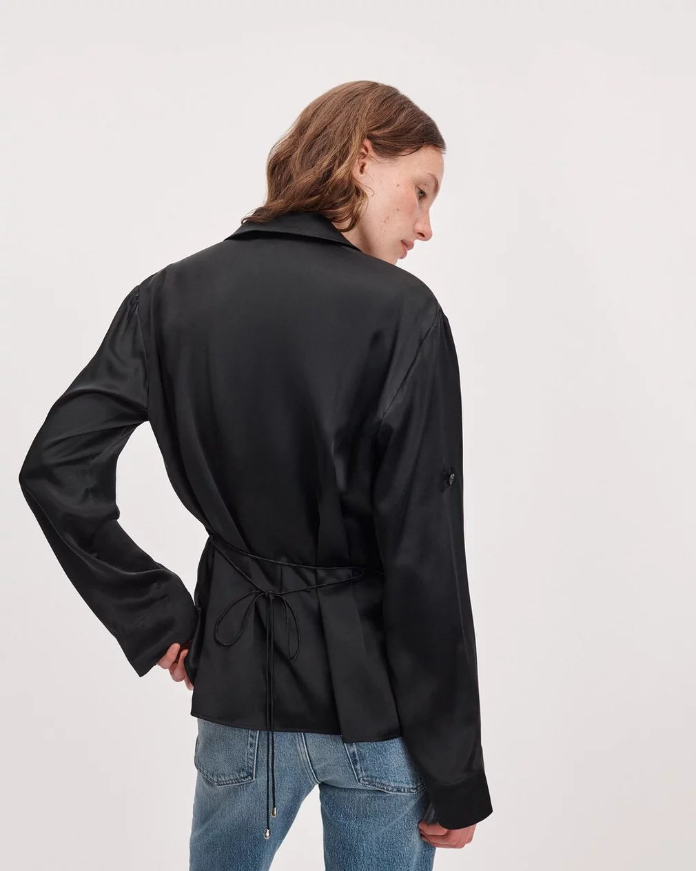 Rag &amp; Bone sonny silk blouse paired with black satin jacket and blue jeans, model standing with hand on hip.