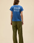 A person with long hair faces away, wearing the DayDreamer Morgan Wallen Somebodies Problem tee in blue and olive green pants against a light beige background, echoing the country star’s iconic style.