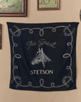 The Stetson Western Bandana by The Great Inc., featuring a black design with a white horse head, "The Great STETSON" text, and a rope with horseshoes border, hangs on the wall beneath framed paintings.