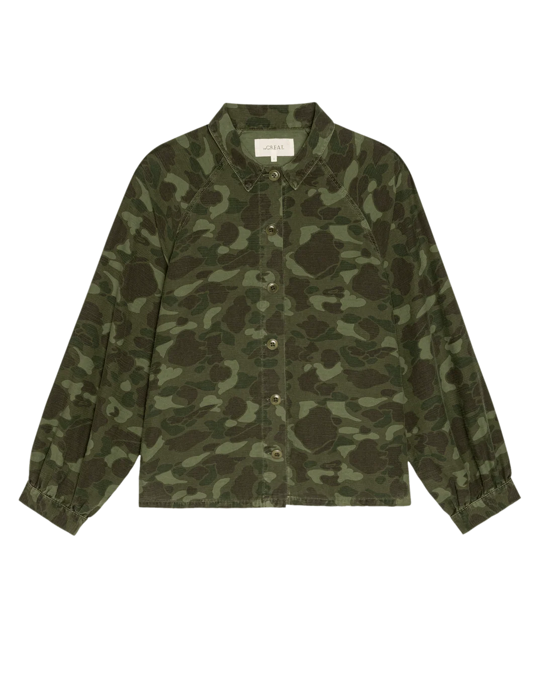 The Commodore Jacket by The Great Inc. is an oversized, green camouflage cotton sateen, long-sleeve button-up with a collar and gathered cuffs, bringing workwear style. Shown on a plain white background.