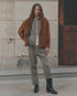 Fleece Sport Sweatpant by The Great Inc. in a relaxed setting, styled with a brown jacket by a stone wall and door.