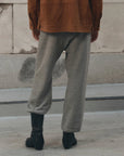 The Fleece Sport Sweatpant by The Great Inc. in black, styled casually with boots and a brown jacket on the sidewalk.