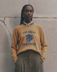 The Great Inc. Fleece Rookie Growling Panther sweatshirt in black, modeled outdoors by a stone wall, casual style.