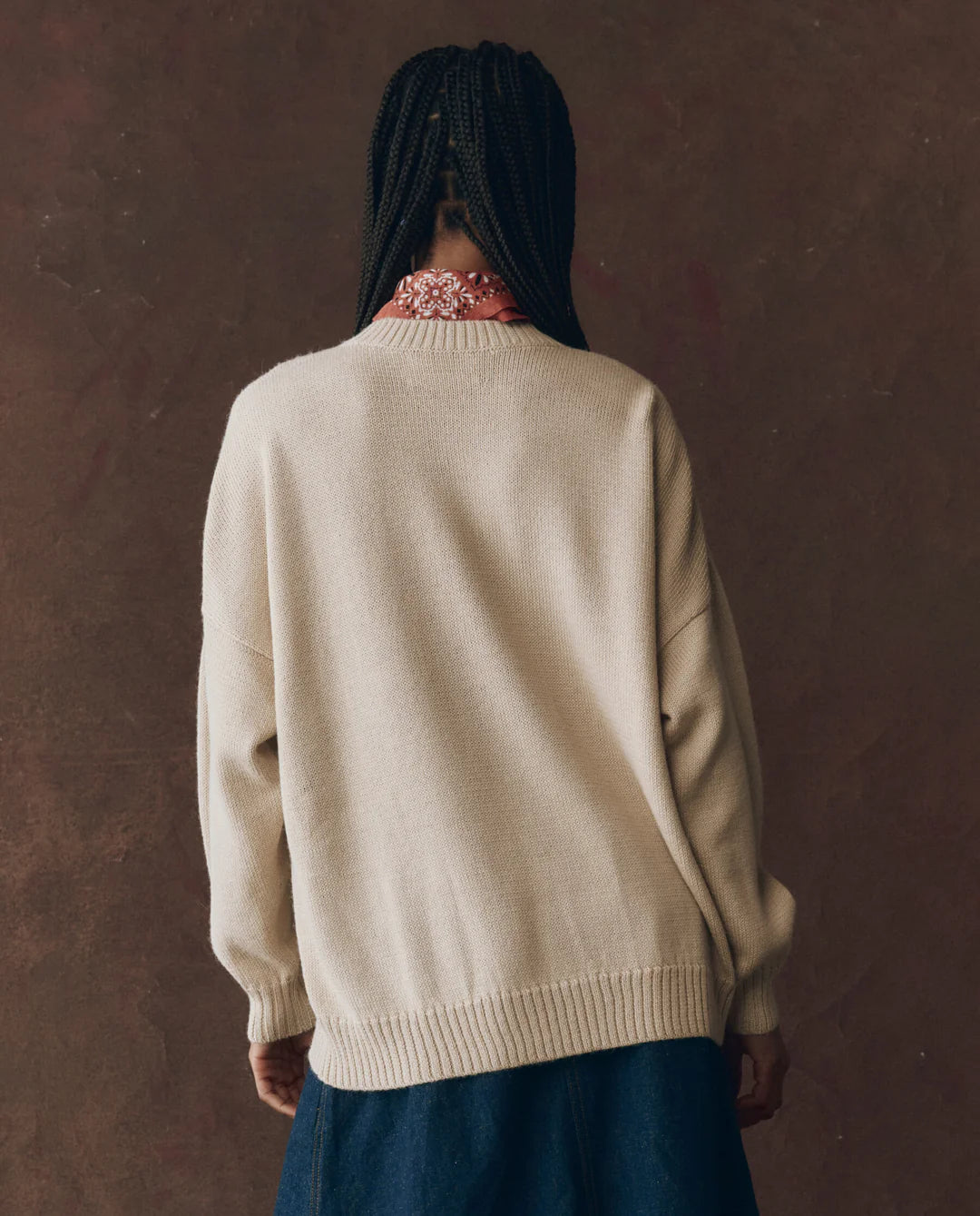A woman wears The Great Inc. Stable Pullover, an oversized crew sweater with a playful horse-head intarsia design.