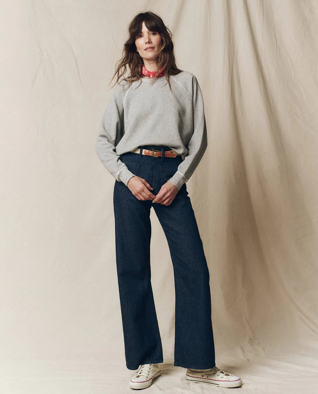 A woman wears The College Sweatshirt by The Great Inc., featuring a bold Wild Panther Graphic, effortlessly paired with blue jeans.
