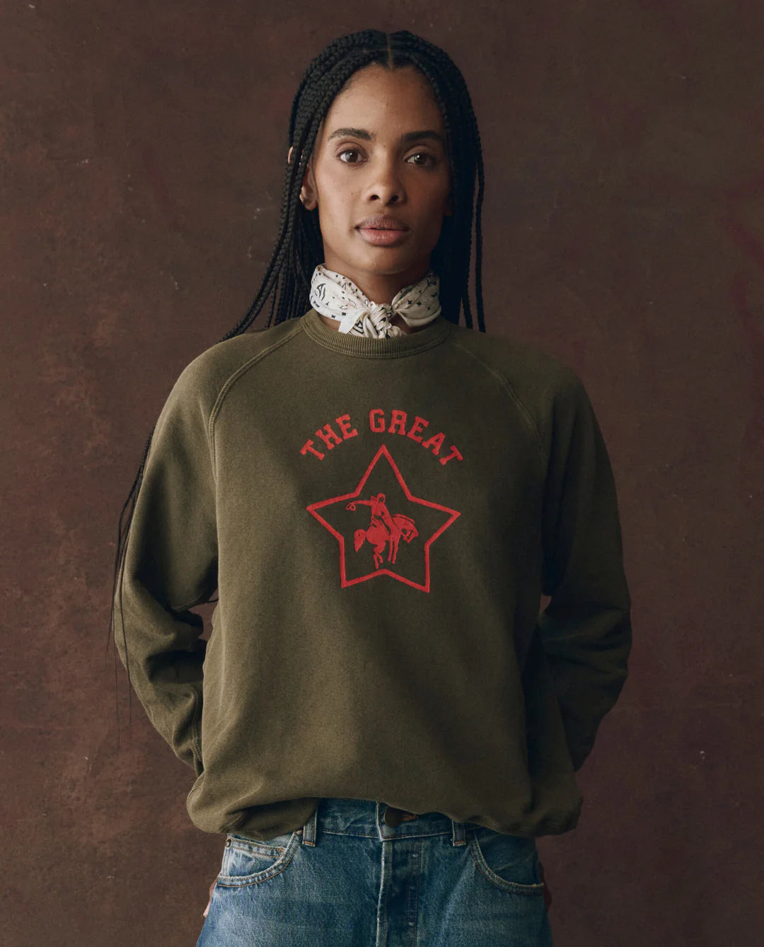 A woman with braids wears The College Sweatshirt by The Great Inc., featuring a bold Wild Panther graphic.