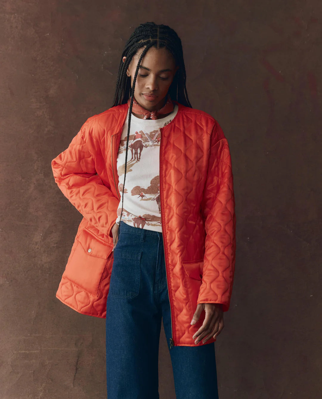 A woman wears The Great Inc. Quilted Liner Parka in red, featuring a removable faux fur collar.