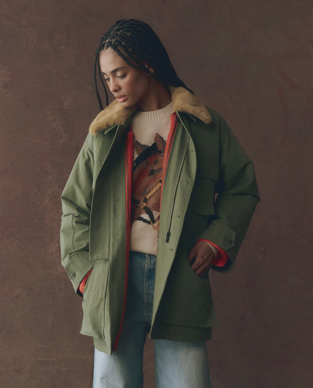 A woman wearing The Quilted Liner Parka by The Great Inc., featuring a green quilted design and removable faux fur collar.