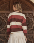 The Great Inc. Field Tee in white styled with a cream skirt, modeled by blonde woman near ornate wooden door.