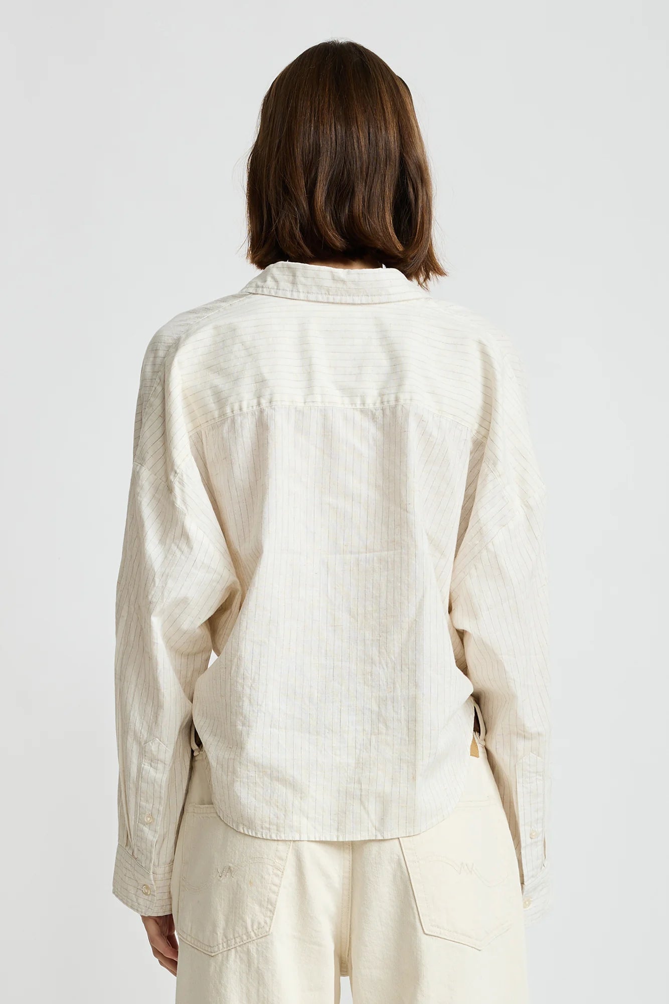 Denimist Twisted Front Shirt in white, shown from behind, worn by model with shoulder-length brown hair.