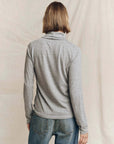 Grey heather turtleneck sweater from The Great Inc. paired with blue jeans, back view.