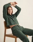 The Harper Shirt by THE SHIRT in a casual setting, model seated with arms raised, facing forward.