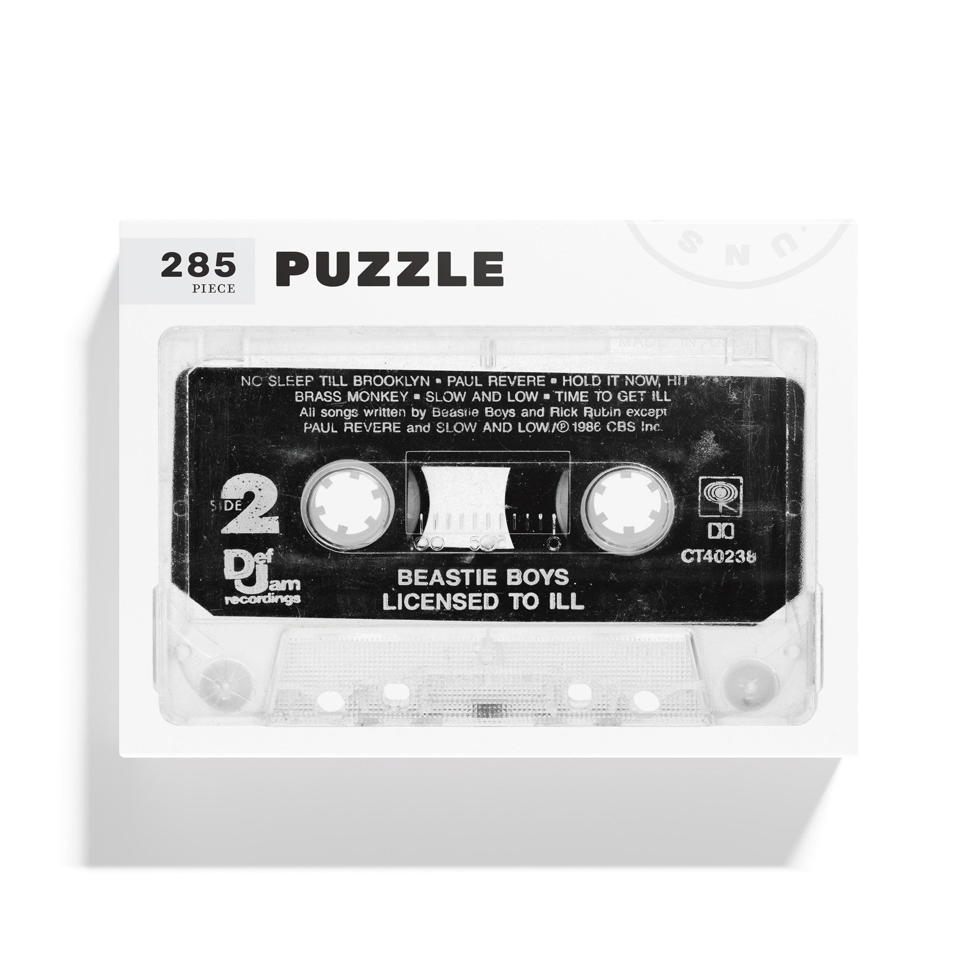 A 285-piece jigsaw puzzle box from Things Unseen featuring a vintage cassette tape design labeled &quot;Beastie Boys Licensed to Ill.&quot; This puzzle pays homage to the iconic debut LP by highlighting detailed song titles and capturing the classic audio tape aesthetic.