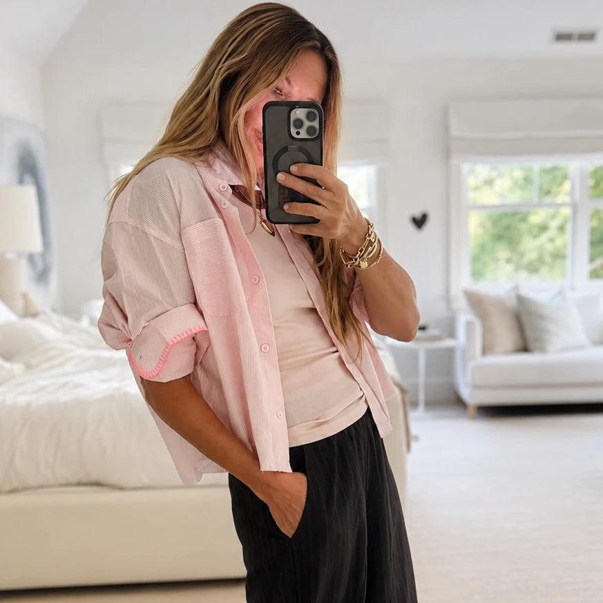 Kerri Rosenthal Tia Love Stripe Shirt with neon pink trim, styled casually with black pants in a modern setting.