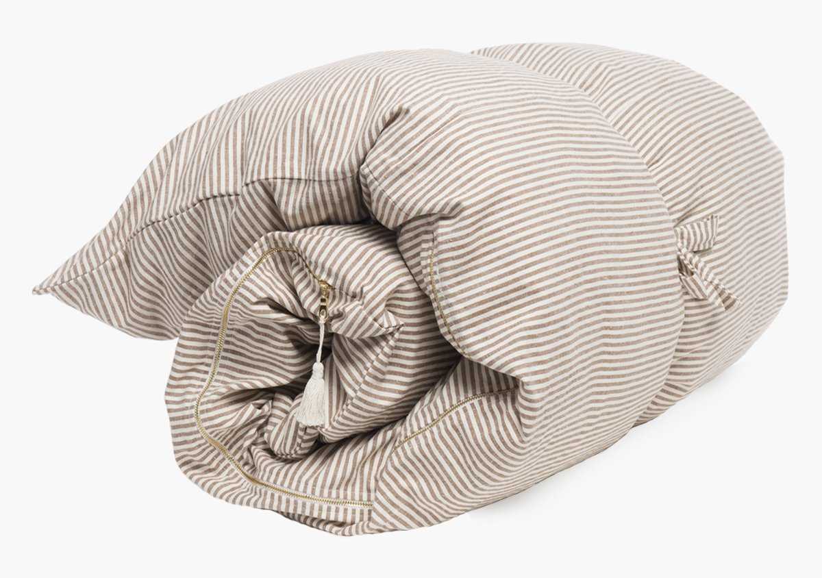 The Hedgehouse Throwbed is a rolled-up comforter in beige and white stripes, featuring a soft cushioned texture and a machine-washable cover, shown on a white background.