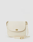 A Turnlock Louis Cream crossbody purse by Clare Vivier with a flap closure and a gold clasp, displayed against a solid white background. The purse has an adjustable strap with a buckle and includes a convenient back pocket.