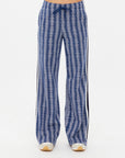 Wearing The Upside's JOIE JETSET STRAIGHT LEG PANT in geometric jacquard with a blue zigzag pattern and black side stripes, the person is shown from torso to legs. These high-waisted, wide-leg pants are made of an organic cotton blend and feature a drawstring waist against a white background.