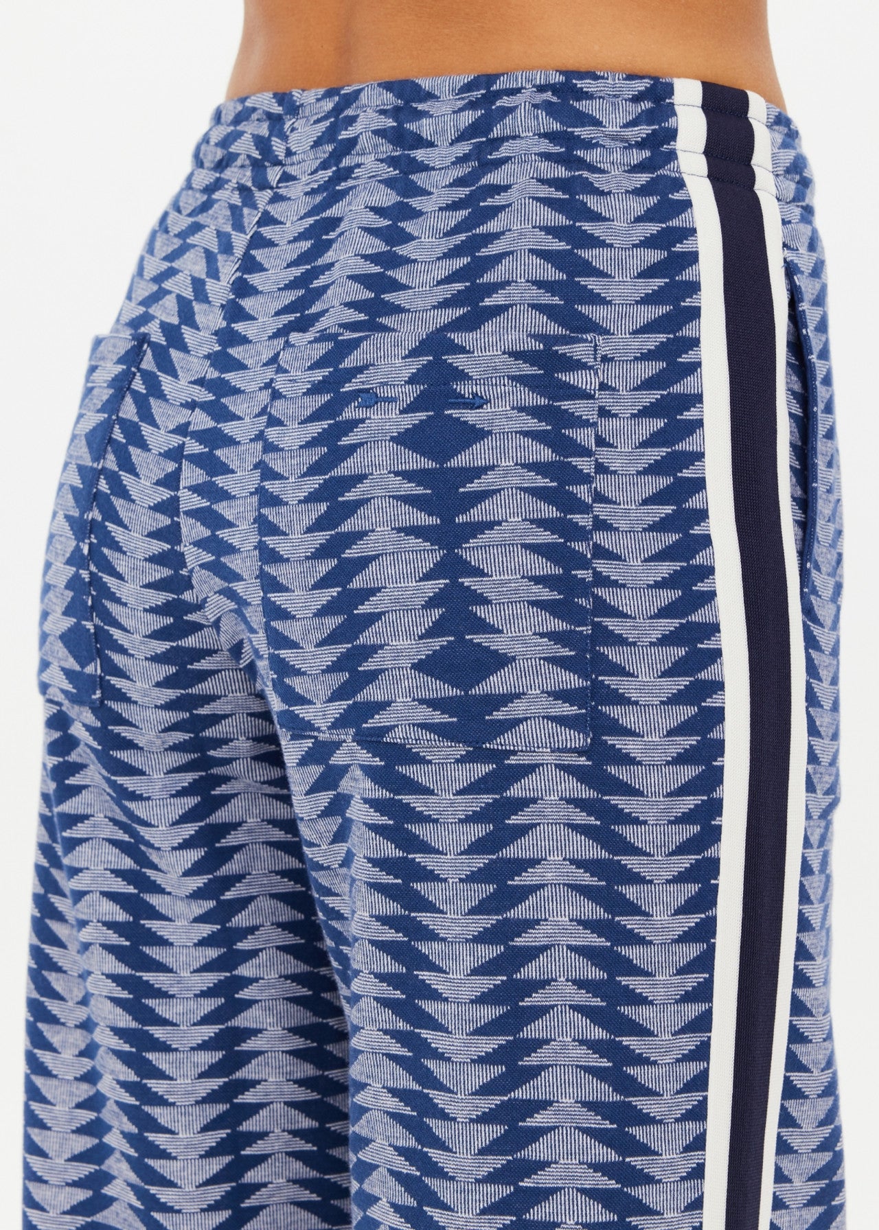 The Upside's JOIE JETSET STRAIGHT LEG PANT, made from an organic cotton blend, features a blue and white patterned fabric with vertical black and white stripes. Its geometric jacquard design gives the loose fit a stylish touch. A photo shows both side and back views.