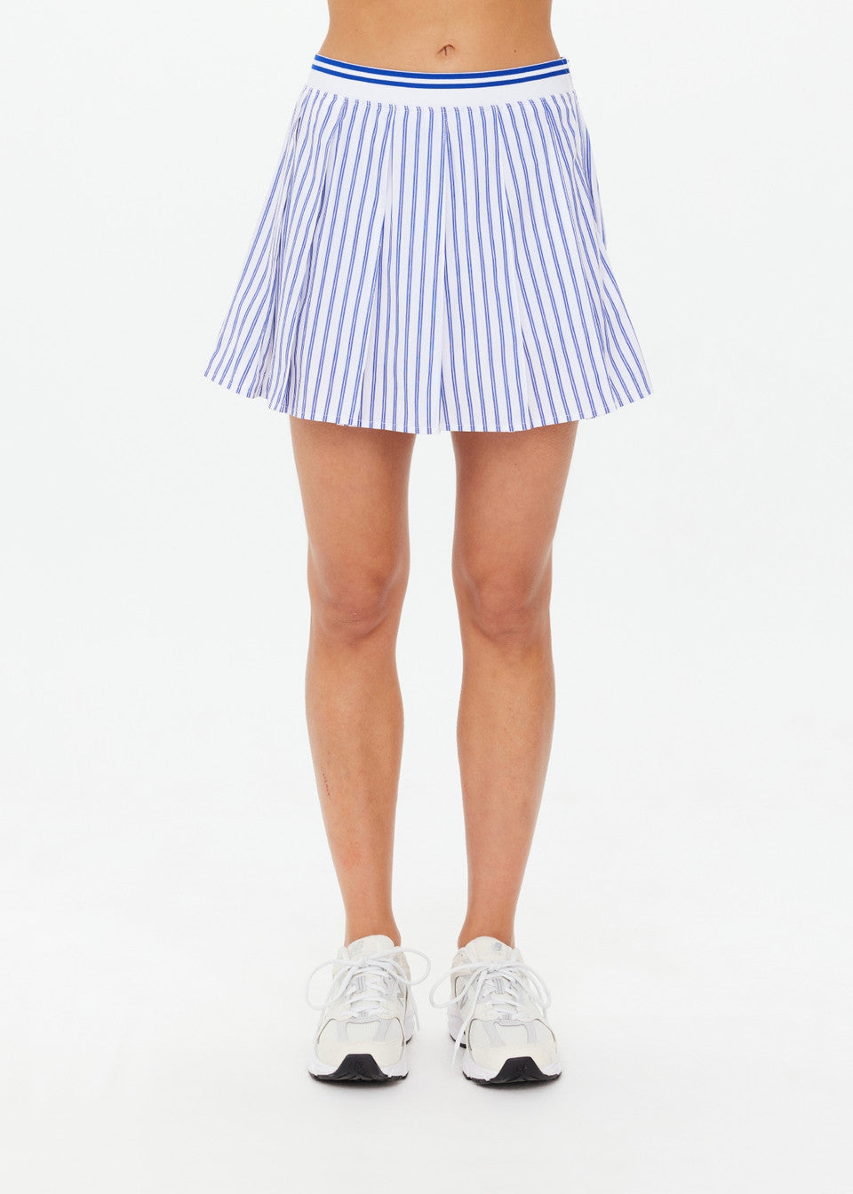 Individual dressed in The Upside's Lyon Xavier Pleated Skirt and white sneakers.