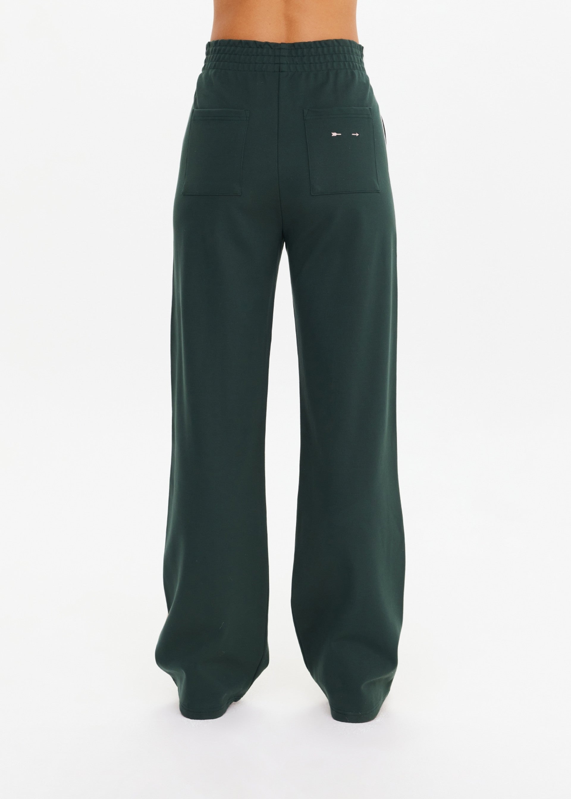 A person models The Upside's MONTE PANT—high-waisted, wide-leg pants made from Lenzing viscose with back patch pockets—against a plain white background.