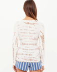 A person with straight brown hair wears The Upside AYLA CHRISSY LONG SLEEVE TOP and blue-and-white striped shorts, standing with their back to the camera against a plain white background.
