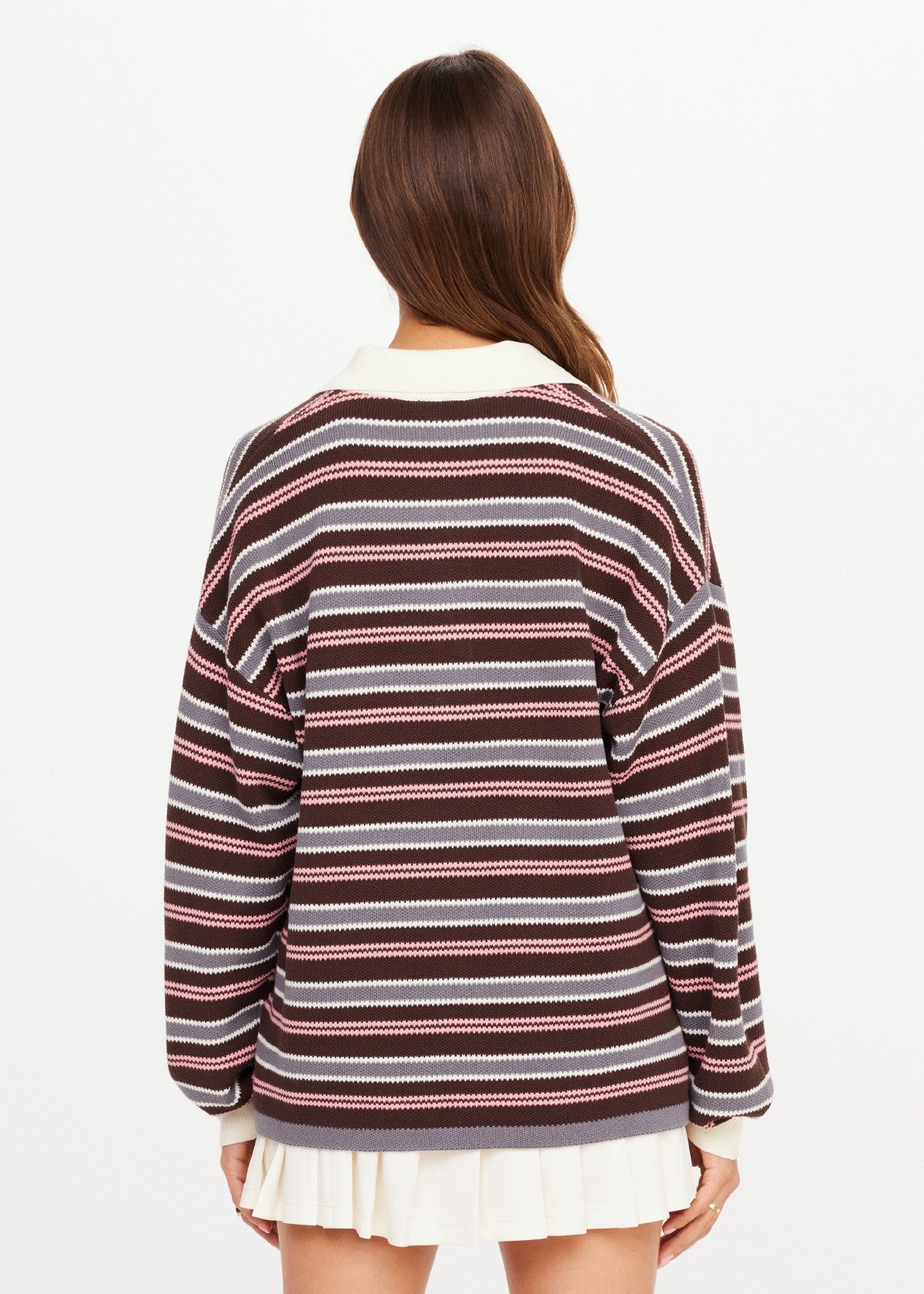 Brown, pink, and white striped knit polo by The Upside with a white pleated skirt, shown from the back.