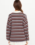 Brown, pink, and white striped knit polo by The Upside with a white pleated skirt, shown from the back.