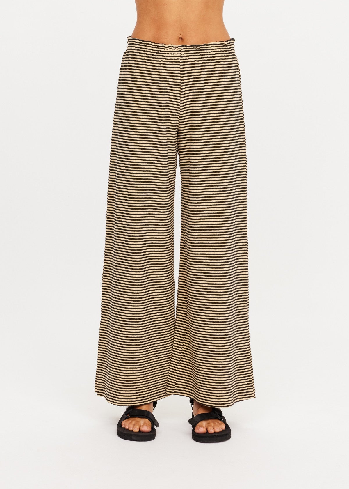 The Upside SANTOS ADRIEL SPLIT PANT in black, styled with black sandals, white background.