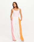 Pink-orange striped wide leg pants by The Upside, styled with a sleeveless pink top, hands in pockets.