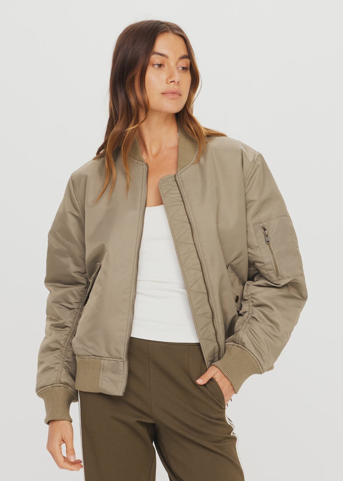 The Upside TRIBUTE BOMBER JACKET in recycled nylon, styled with a white tank and olive pants on a neutral backdrop.